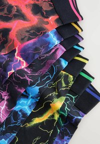 Chaussettes colorées arborant des motifs abstraits d'éclairs dans des nuances de rouge, bleu, violet et jaune, avec un tissu noir et des poignets rayés contrastants.