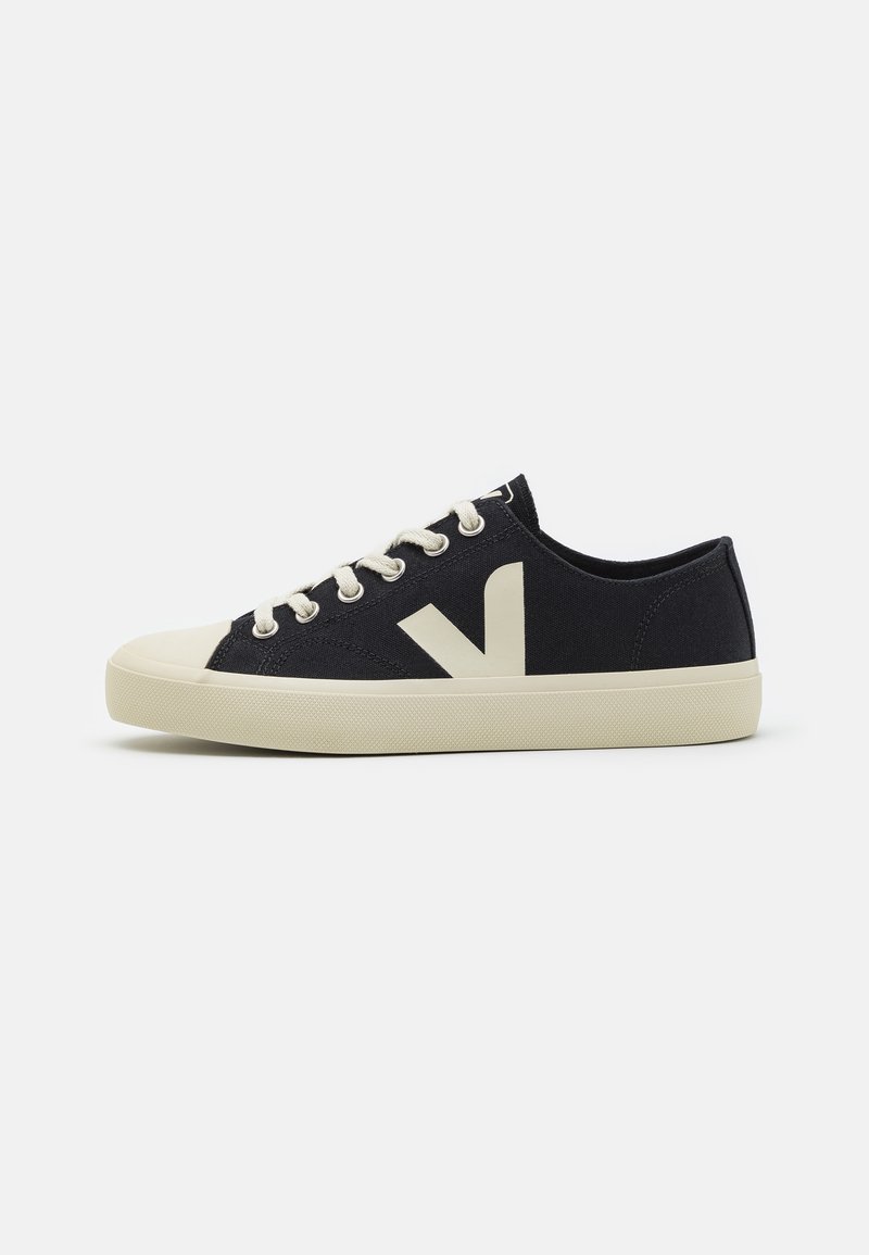 Sneakers de lona azul-marinho de cano baixo com sola de borracha color creme, cadarços brancos e um logótipo bege proeminente na lateral. Design clássico com detalhes texturizados.
