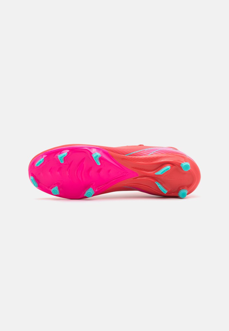 Suola di scarpa sportiva di un vivace rosa con borchie turchesi, caratterizzata da una superficie testurizzata e un design affusolato per un'ottima aderenza.