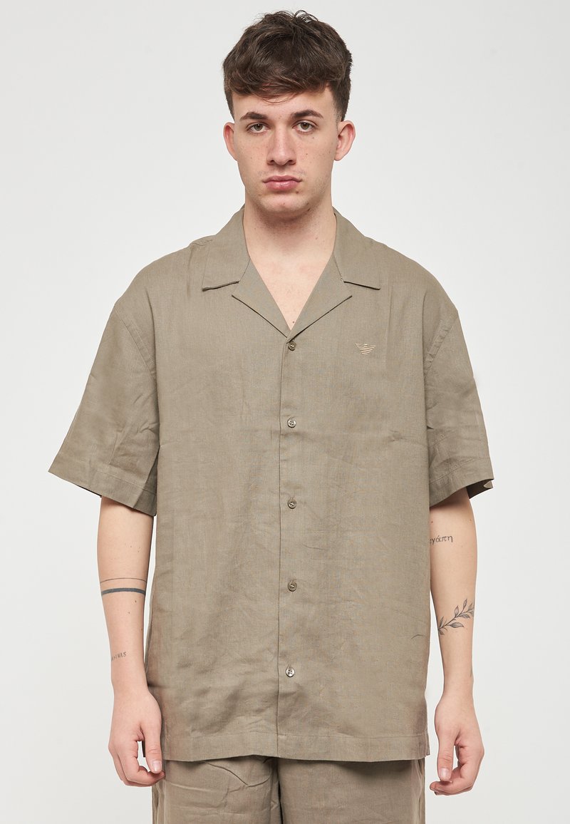 Kortærmet, kravebluse lavet af letvægts, struktureret beige stof med en subtil glans, der har en knap-til-forside og en lille logodetalje.