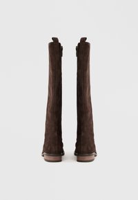 Botas altas de camurça castanhas com uma textura suave, fechos de correr laterais e saltos de madeira empilhados. Silhueta limpa e design ajustado.