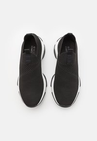 Fekete, hálós anyagból készült slip-on sportcipők, melyek texturált felülettel, elasztikus felső szegéllyel és fehér gumitalppal rendelkeznek. Fűzők nincsenek.
