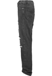 Jeans de mezclilla negra con corte ajustado, que presentan detalles rasgados a lo largo de las piernas y un diseño tradicional de cinco bolsillos.