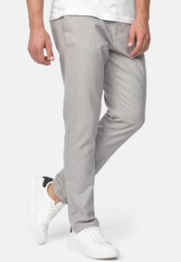 Pantalones gris claro hechos de una tela suave. Tienen un corte ajustado, bolsillos laterales y se combinan con zapatillas blancas con detalles en negro.