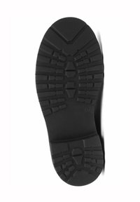 Semelle de chaussure en caoutchouc noir présentant un motif de semelle texturé avec des rainures et des crêtes pour une meilleure adhérence et traction.