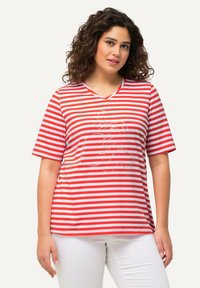 Camiseta de manga corta con cuello en V a rayas rojas y blancas, con un diseño gráfico en el frente. Tela suave, corte relajado. Se lleva con pantalones blancos.