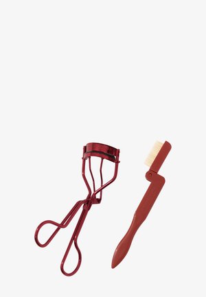 Récourbe-cils en métal rouge avec un peigne, doté d'une poignée lisse, d'un côté en plastique beige et d'une forme arrondie pour une prise en main facile.