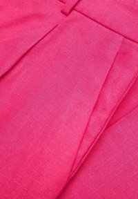 Tissu rose vif avec une finition texturée ; présente des plis et des lignes nettes, mettant en valeur une couleur unie et une surface lisse sans motifs.