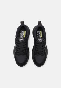 Baskets noires en maille et en daim. Elles comprennent des lacets, une languette de traction et une semelle en caoutchouc texturée. Comprend le logo Vans sur la languette et le côté.