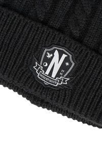 Bonnet en tricot noir avec une texture côtelée, un patch logo bien visible, et un motif en forme de bouclier avec la lettre "N" et des éléments décoratifs.
