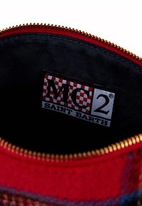 Pouch rosso con zip dalla texture morbida, con interno nero e un'etichetta che mostra "MC2 SAINT BARTH" in un design a quadretti.