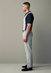 Granatowa koszulka polo w białe pionowe paski, połączona z jasnoszarymi spodniami i ciemnogranatowymi mokasynami. Slim fit, krótki rękaw, klasyczny kołnierzyk.