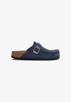 Sabots en daim bleu marine pour hommes avec une boucle argentée ajustable et un semelle en liège brun, semelle plate noire, vue de côté sur fond blanc.