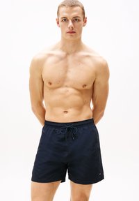 Μπλε ναυτικό μαγιό με ελαστική μέση και κορδόνι. Κατασκευασμένο από ελαφρύ ύφασμα, διαθέτει διακοσμητικό λογό τυπο στο τελείωμα.