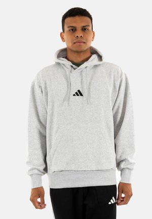 Sudadera de algodón gris con bolsillo canguro, capucha con cordón y logo triangular negro en el pecho. Corte relajado con puños acanalados.