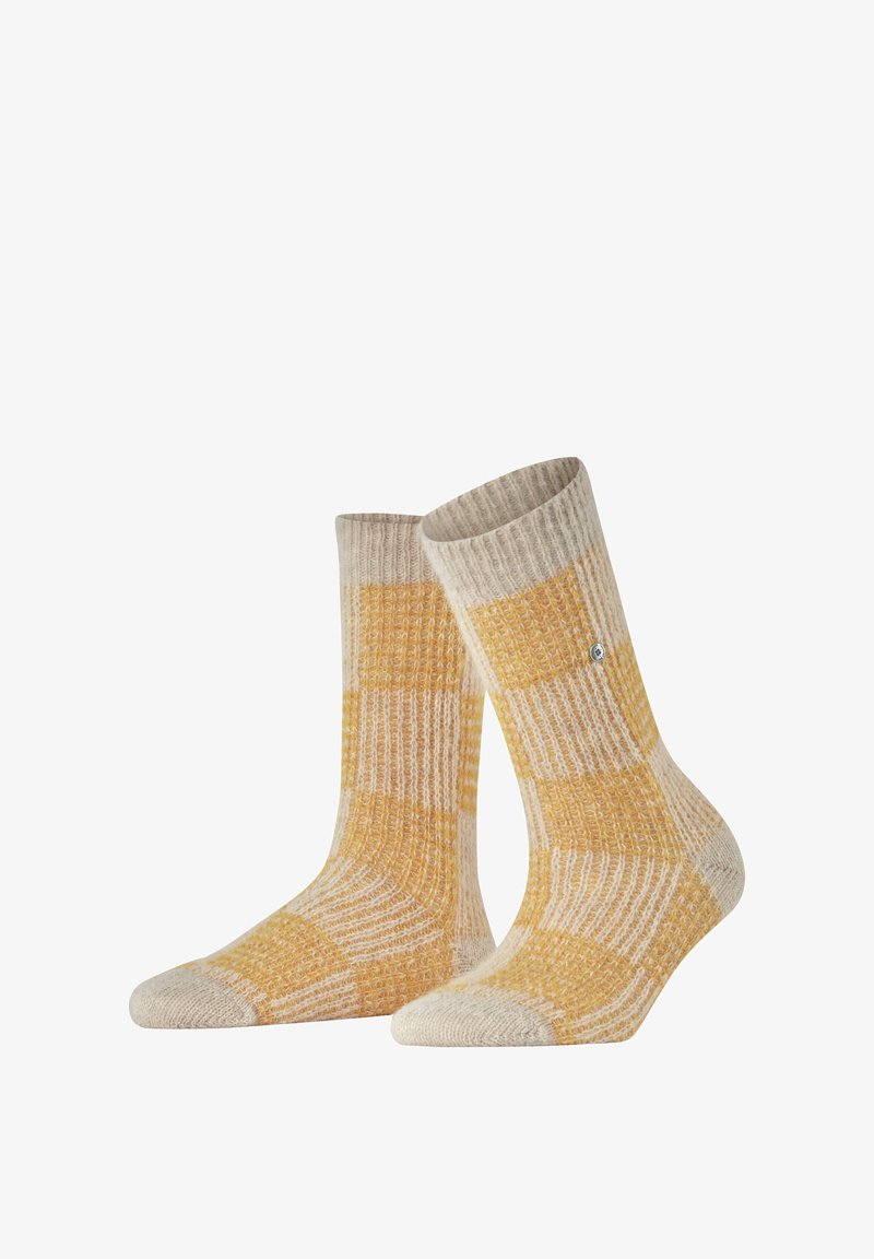 Gelbe und beige gemusterte Socken mit einem gerippten Design, das eine verstärkte Zehe und Ferse aufweist. Das Material hat ein gemütliches, strukturiertes Aussehen.