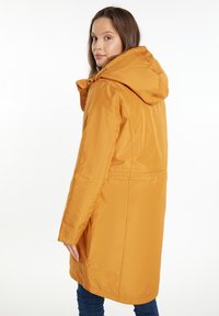 Gul vandtæt parka med hætte, der har en glat tekstur, lynlås lukning og en justerbar talje for en tilpasset pasform.