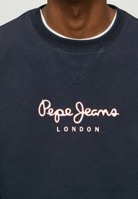 Navy sweatshirt with a crew neckline, featuring pink embroidered "Pepe Jeans LONDON" logo on the chest. Cotton fabric with a soft texture.