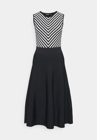 Svart klänning med ärmlös bodice som har vita chevronränder och en figursydd midja, vilket leder till en utsvängd kjol som når till knäna.