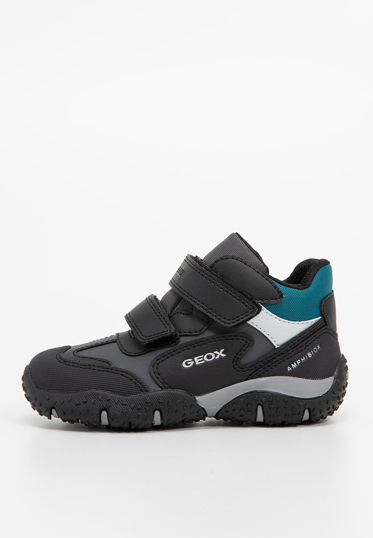 Schwarzer und grauer Sportschuh mit zwei Klettverschlüssen, strukturiertem Obermaterial und einem Teal-Akzent. Verfügt über eine robuste Sohle für besseren Halt.