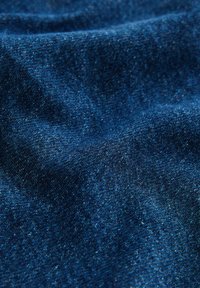 Tessuto denim di colore blu intenso, con una superficie strutturata e sottili variazioni, caratteristico del materiale in cotone intrecciato.