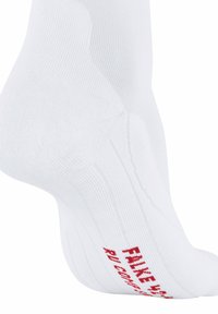 Primo piano di una calza bianca da caviglia con una texture a coste e un testo rosso sul fondo che recita "FALKE".
