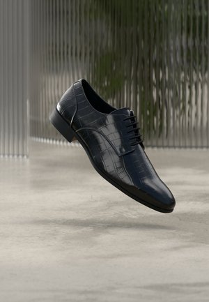Chaussure habillée en cuir bleu foncé avec un bout effilé et élégant, ornée d'un motif texturé façon crocodile. Elle présente un design à lacets et un détail discret sur la semelle.