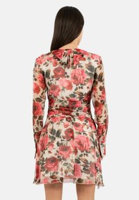 Bloemige jurk van doorschijnende stof met grote roze rozen en groene bladeren, lange mouwen, een getailleerde taille en een vloeiende rok met een zoom.