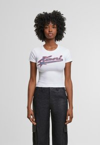Camiseta blanca ajustada de manga corta con un gráfico colorido de "Keni" en rojo y azul, combinada con pantalones cargo negros que cuentan con bolsillos laterales.