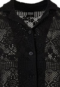 Schwarze gehäkelte Strickjacke mit Knopfleiste, ausgestattet mit einem strukturierten Spitzenmuster und einem klassischen Kragen, der ein offenes, luftiges Design präsentiert.