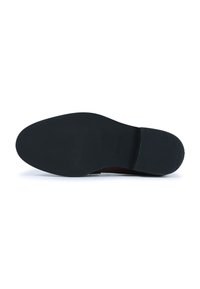 Suela de zapato de goma negra, que presenta una superficie suave con estrías texturizadas para mayor agarre y una forma ligeramente curvada en el talón.