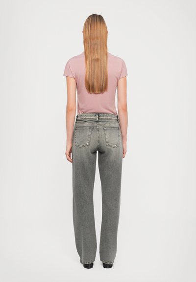 Jeans de pierna ancha grises combinados con una camiseta ajustada rosa claro, que presenta una cintura clásica y bolsillos traseros. Diseño simple y casual.