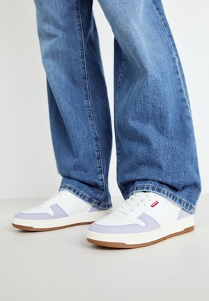 Baskets basses blanches avec des accents violet clair et des semelles en caoutchouc marron. Matériaux synthétiques et textiles texturés. Design à lacets avec détail de logo.