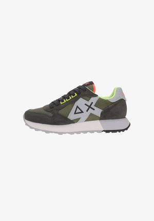 Zapatilla deportiva verde y gris con cordones negros, detalles en amarillo neón, suela blanca y logo geométrico en el lateral, mostrada de perfil derecho.