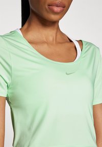 Heled roheline sportlik T-särk lühikeste varrukatega, ringikujuline kaelus ja keskel õrn hall Nike logo. Sile kangastekstuuri.