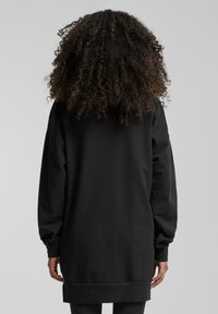 Black sweatshirt with long sleeves, relaxed fit, and ribbed hem. Smooth texture with no visible patterns or hardware details.