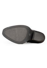 Suela de un zapato negro con una parte inferior de goma texturizada. Presenta un tacón liso y un patrón de rayas horizontales para mayor agarre.