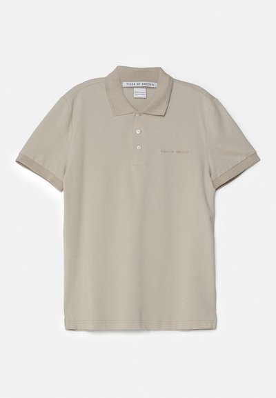 Beige puhkepaiste triiksärk, mis on valmistatud puuvillast, klassikalise krae, lühiheitega, kahe nööbiga ja diskreetse logo tikandiga rinnas.