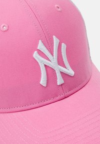 Rózsaszín textil baseball sapka strukturált kialakítással. Fehér hímzett 'NY' logóval és varrott díszítéssel a napellenzőn.