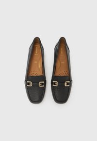 Mocasini negri din piele cu detaliu de cataramă aurie și tălpi căptușite, o pereche așezată plan pe fundal alb.