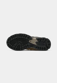 Semelle de chaussure avec une bande de roulement noire multi-motifs pour la traction, montrant des rainures profondes et du caoutchouc texturé pour l'adhérence et la durabilité.