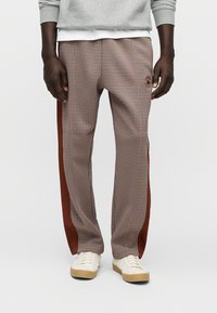 Καρό παντελόνια σε καφέ, λευκό και μπλε με κόκκινη πλευρική ρίγα. Κατασκευασμένα από ελαφρύ ύφασμα με άνετη εφαρμογή και ελαστική μέση.