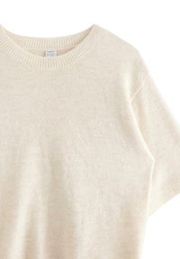 Beżowy sweter dzianinowy z krótkimi rękawami i okrągłym dekoltem. Materiał ma miękką teksturę i subtelny melanzowy wzór. Widoczna metka marki.