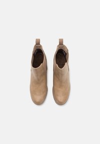 Bottines en cuir beige avec des panneaux élastiques sur les côtés, bouts ronds et languettes au niveau du talon. Texture lisse et semelles en caoutchouc profil bas.