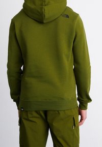 Oliwkowa zielona bluza z kapturem z kieszenią kangura, teksturowaną tkaniną, ściągaczami na mankietach i dole oraz małym czarnym logo na górnej części pleców.