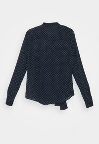 Námořnická modrá košile s dlouhým rukávem a bílými puntíky, s límcem na knoflíky a zakřiveným lemem. Lehký, průsvitný materiál.