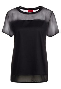 Camiseta negra con una capa superior transparente, cuello redondo clásico, mangas cortas y un cuerpo inferior negro sólido. Etiqueta visible en el interior.