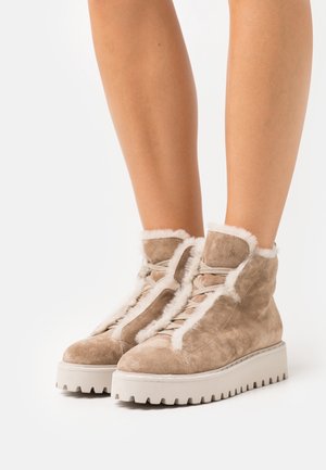 Botines de ante topo con forro de felpa blanca, parte delantera con cordones y suela de goma blanca gruesa con borde dentado.