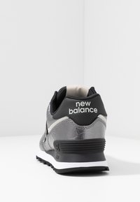 Sneaker New Balance nero e argento con una parte superiore testurizzata, un colletto imbottito e una suola intermedia bianca. Presenta un logo sul tallone.