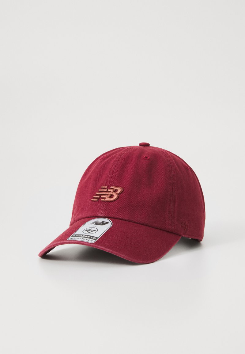 Red cotton baseball cap with a curved brim, embroidered "NB" logo, and a fabric label on the front. Adjustable strap at the back.